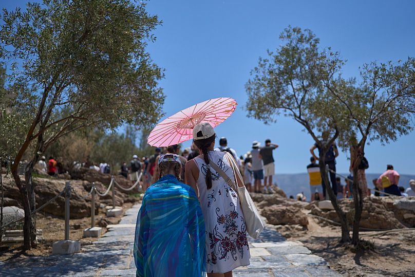 Tourists with an umbrella walk at the foot Acropolis Hill.