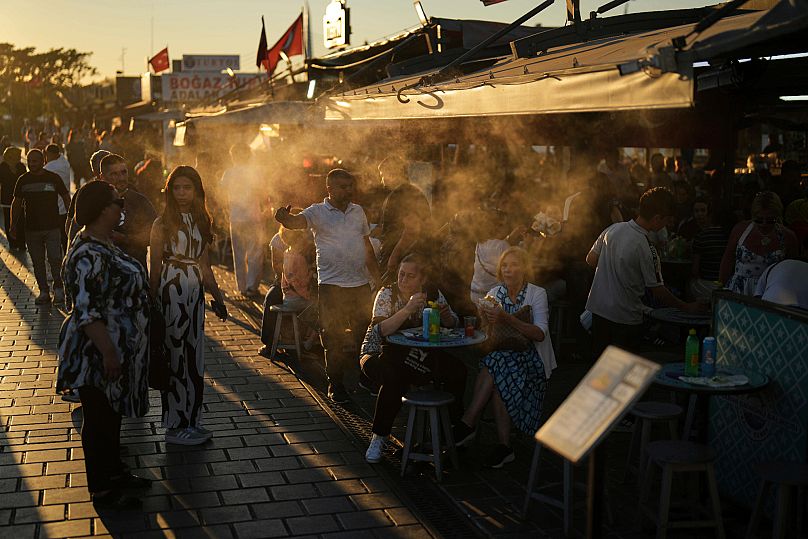 Customers eat at a popular fish restaurant as water is sprayed to cool the area on a summer day, in Istanbul.