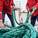 Εργαζόμενοι πλοίου χειρίζονται σχοινιά πρόσδεσης και ασφάλισης φορτίου