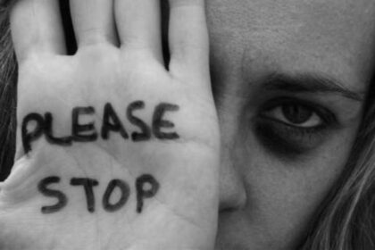Γυναίκα υψώνει το χέρι της με το μήνυμα Please Stop, σε συμβολική εικόνα κατά της ενδοοικογενειακής βίας