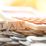 Ξύλινα γράμματα TAX πάνω σε έγγραφα και κέρματα