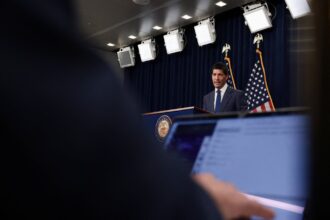 Αμερικανός αξιωματούχος μιλά μπροστά από σημαίες των ΗΠΑ
