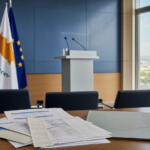 Κυπριακή αίθουσα ενημέρωσης με κρατική και ευρωπαϊκή σημαία και οικονομικούς φακέλους στο προσκήνιο