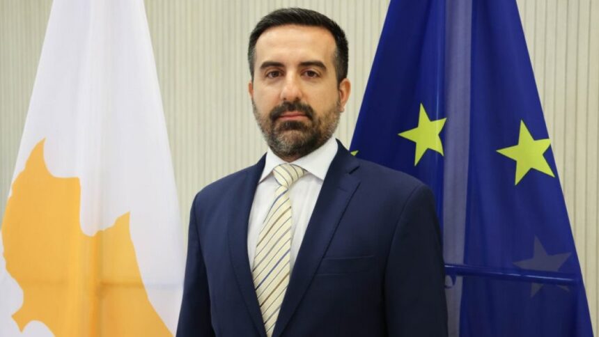 Ο υφυπουργός Μετανάστευσης Νικόλας Ιωαννίδης μπροστά στις σημαίες της Κύπρου και της Ευρωπαϊκής Ένωσης