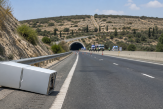 Συμβολική απεικόνιση κλειστού αυτοκινητόδρομου με ψυγείο στο έρεισμα και οχήματα έκτακτης ανάγκης κοντά σε σήραγγα