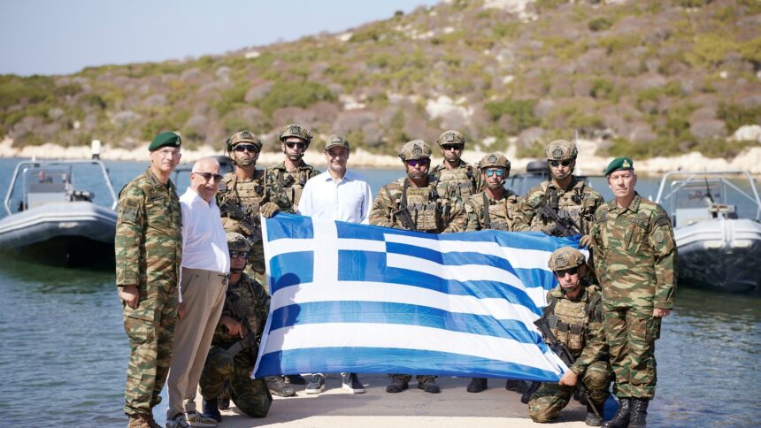 Ο Κυριάκος Μητσοτάκης με στελέχη των Ενόπλων Δυνάμεων και ελληνική σημαία κατά την επίσκεψη στο ακριτικό σύμπλεγμα