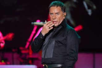 Ο Γιώργος Μαζωνάκης τραγουδά στη σκηνή με μαύρο πουκάμισο.