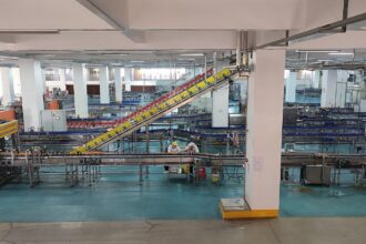 Γραμμή εμφιάλωσης με εργαζόμενους και βιομηχανικούς μεταφορικούς ιμάντες σε εργοστάσιο στη Χεγιουάν της Κίνας