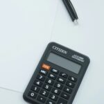Μαύρη αριθμομηχανή γραφείου και στιλό πάνω σε λευκό χαρτί
