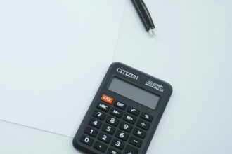 Μαύρη αριθμομηχανή γραφείου και στιλό πάνω σε λευκό χαρτί