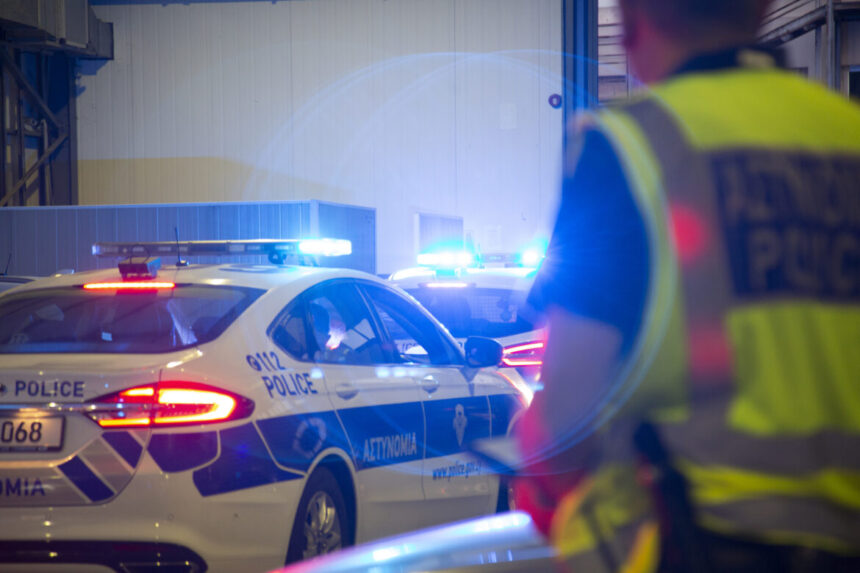 Περιπολικά της Αστυνομίας Κύπρου με αναμμένους φάρους και αστυνομικός με ανακλαστικό γιλέκο