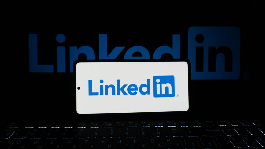 Η εφαρμογή LinkedIn σε πραγματικό κινητό τηλέφωνο μπροστά από υπολογιστή
