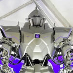 Ο Neo1 της NeodraDynamics μπροστά σε μωβ εταιρικό εκθεσιακό περίπτερο.