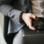 Άνδρας κρατά κινητό τηλέφωνο δίπλα σε φορητό υπολογιστή
